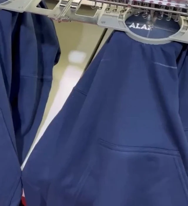 Máquina de bordado trabajando sobre una sudadera real en el taller